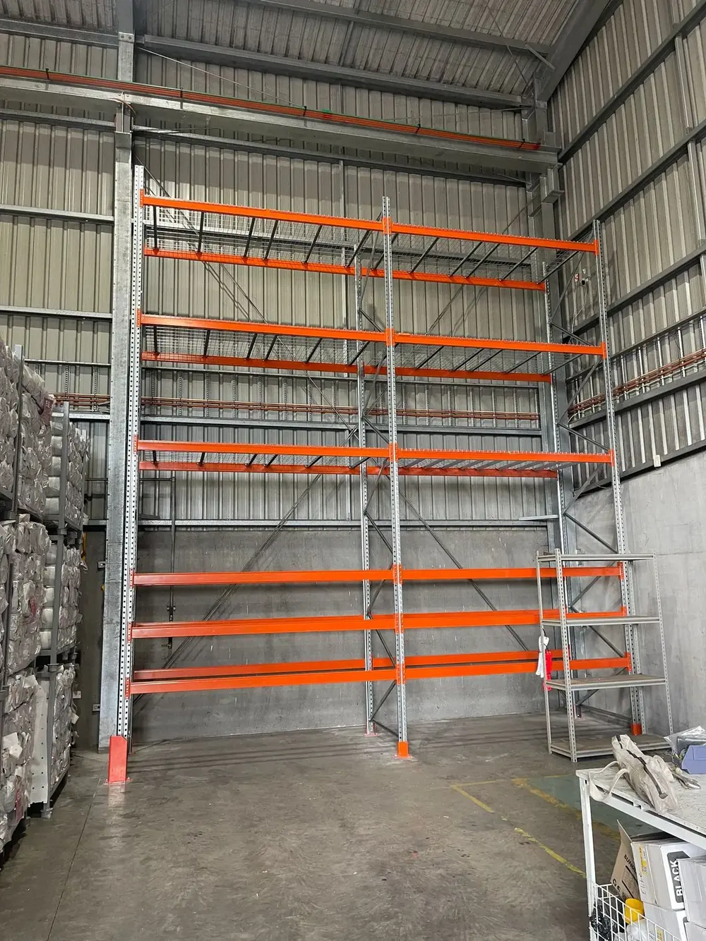 Tall orange long-span shelving installed in a warehouse bay