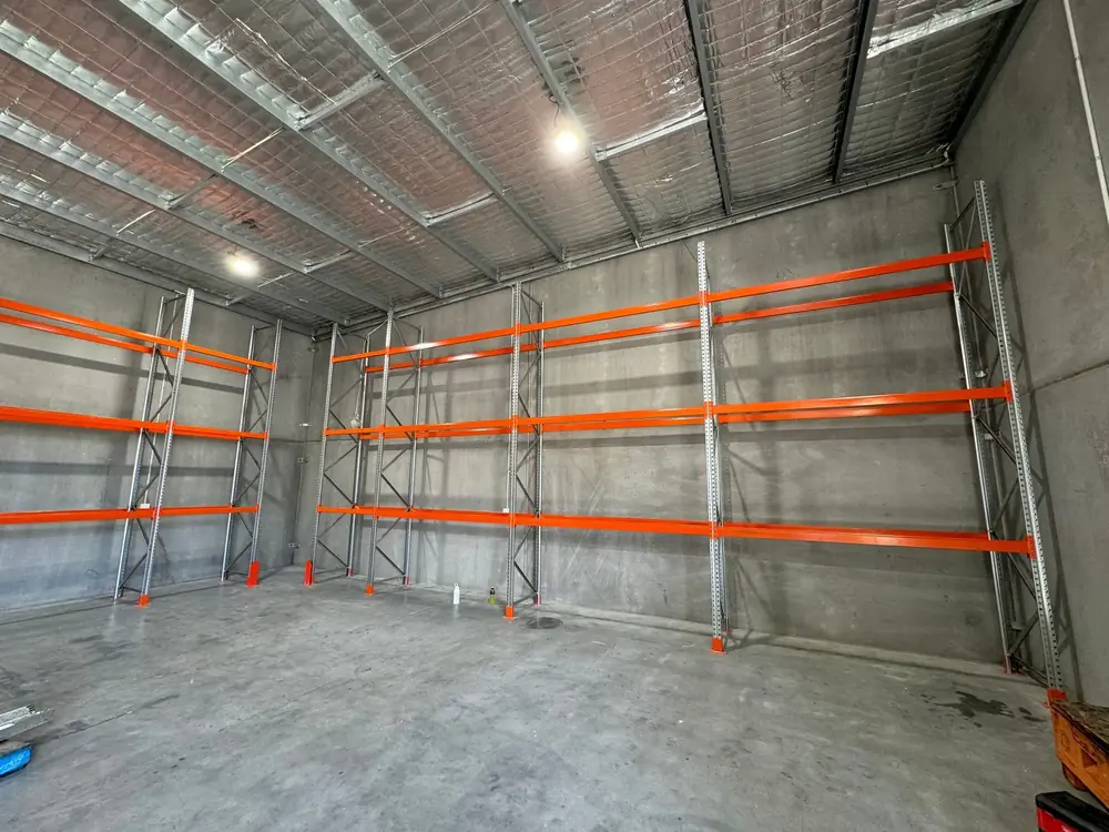 Orange pallet racking installed along a warehouse wall