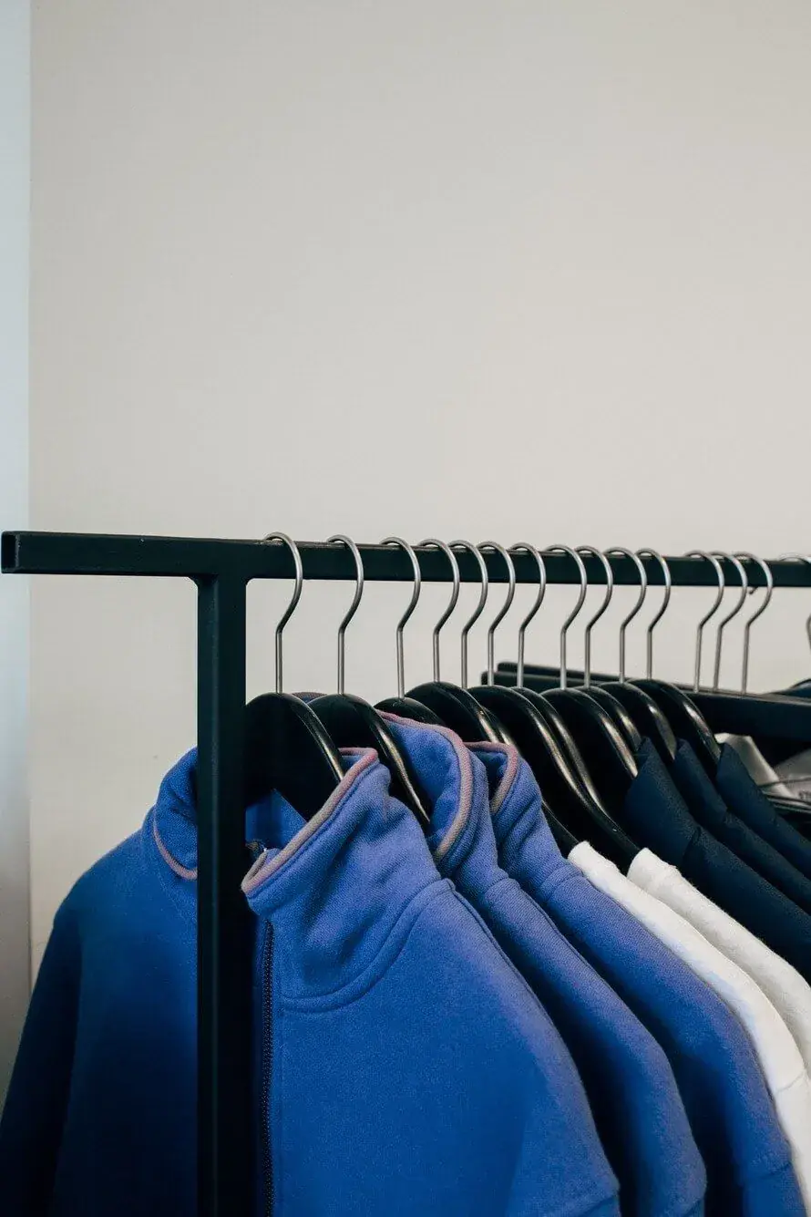 Blue garments hanging on a black retail clothing rack