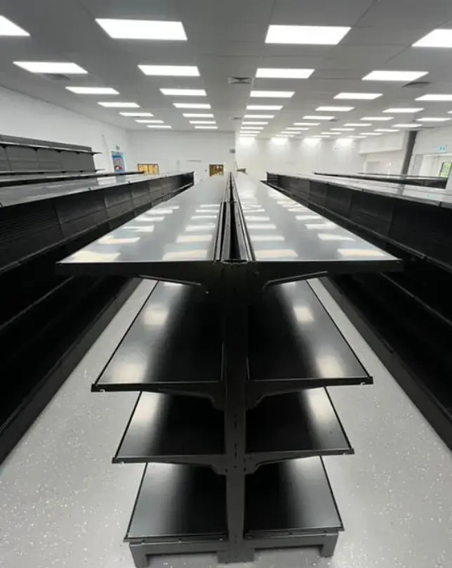 Black retail gondola shelving arranged in long store aisles